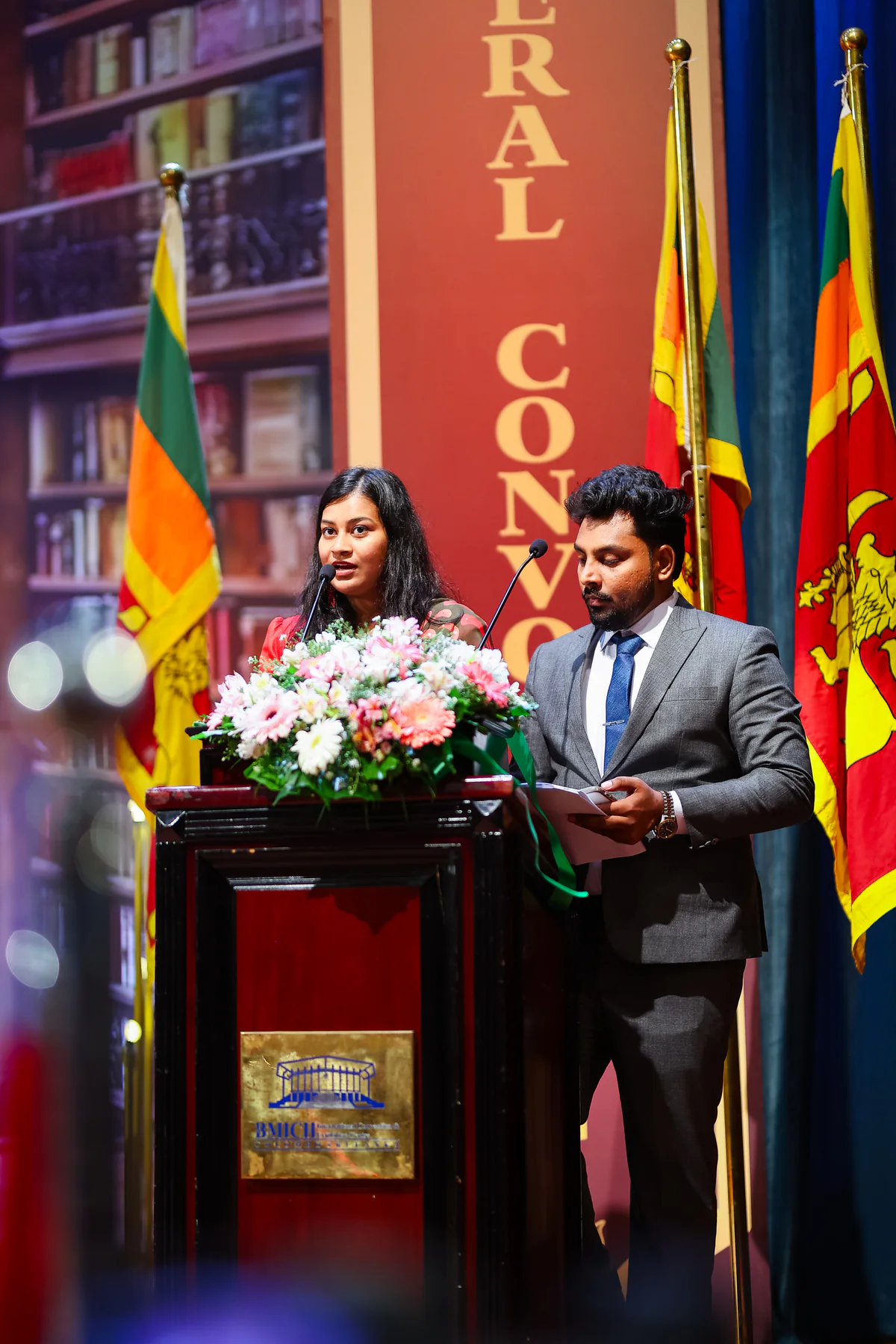 The convocation hosts speaking from the flower-lined podium