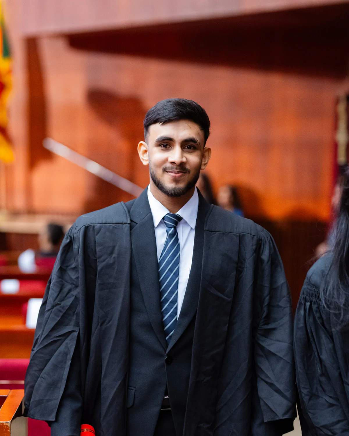 A graduate in ceremonial attire holding a certificate