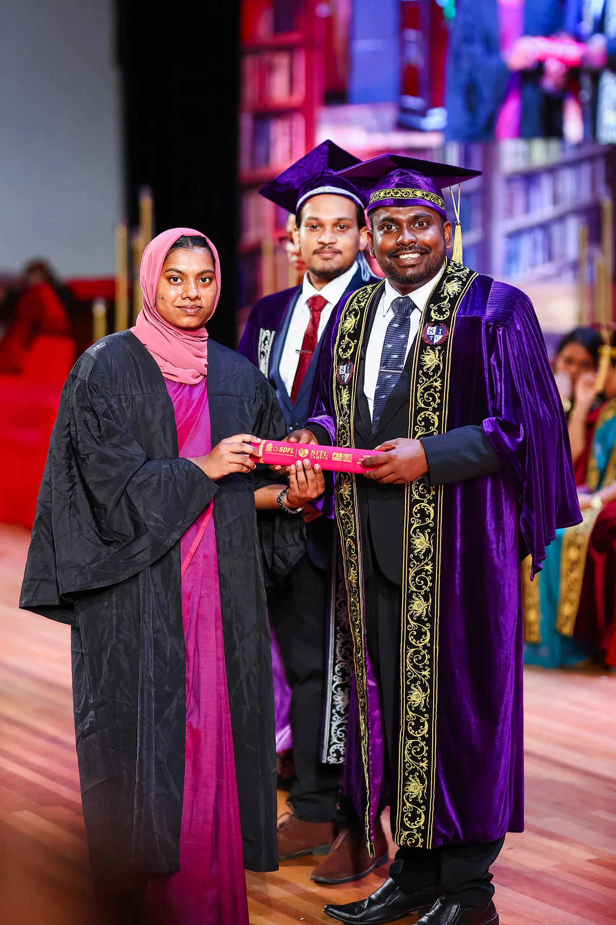 A graduate and academic representatives marking a presentation moment
