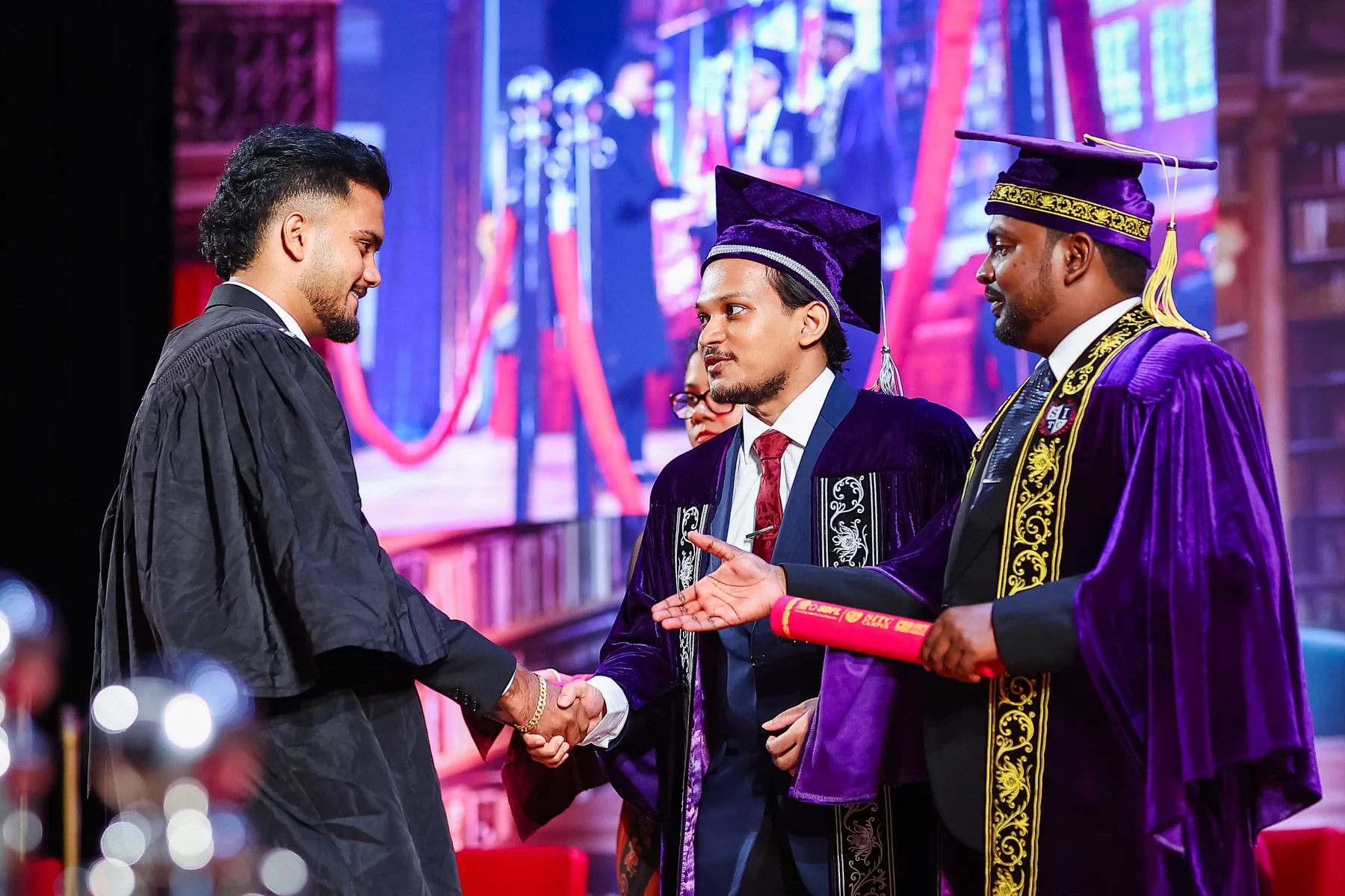 A graduate and academic representative during a stage presentation
